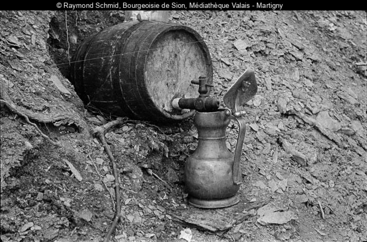 Photo en noir-blanc d'un fût de vin qui remplit une channe