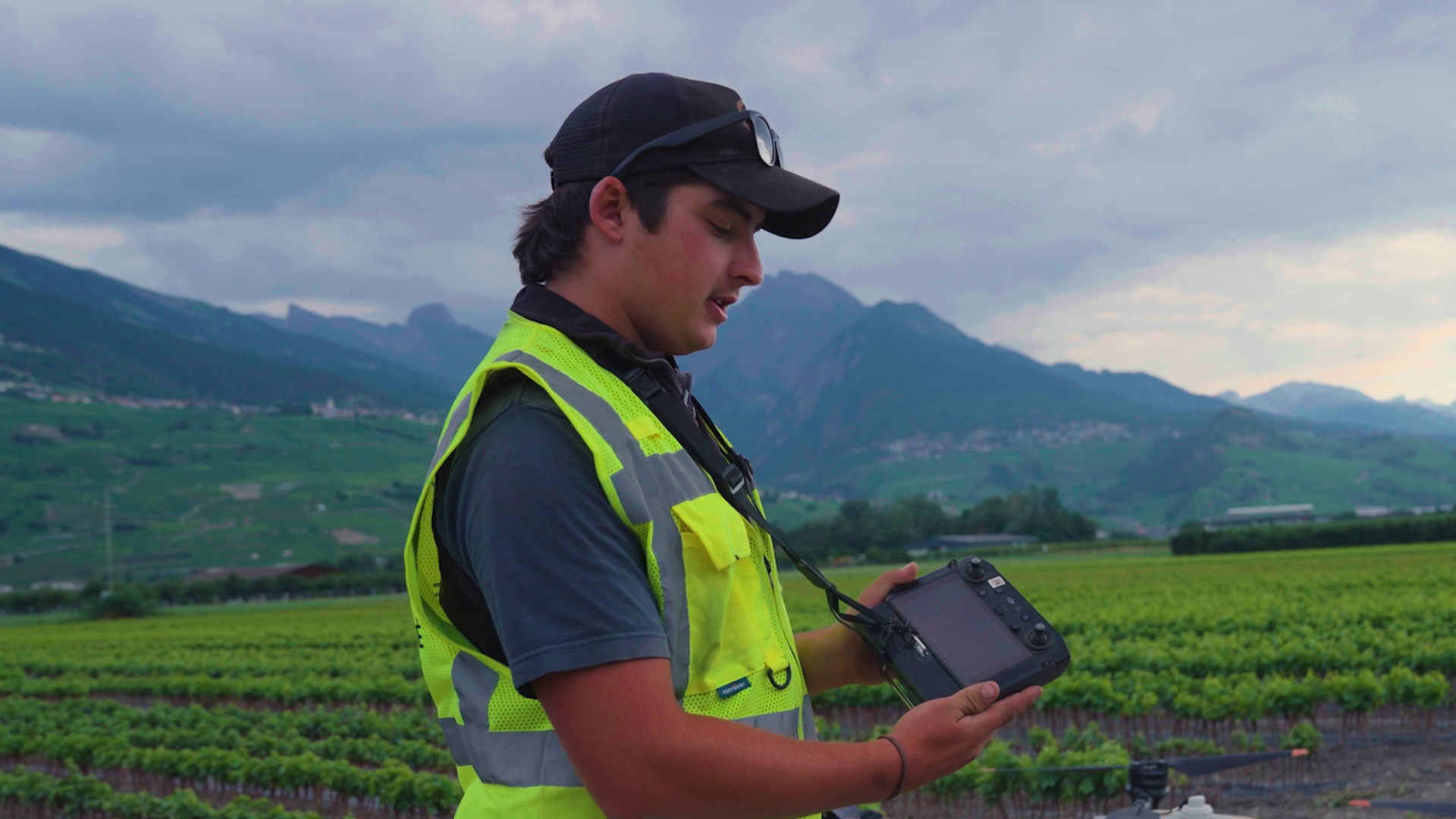 Le jeune apprenti viticulteur montre la manette du drone d'épandage dans le vignoble valaisan